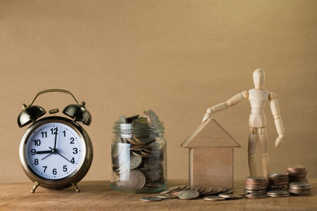 Ahorro acumulado junto a una casa en miniatura y un reloj