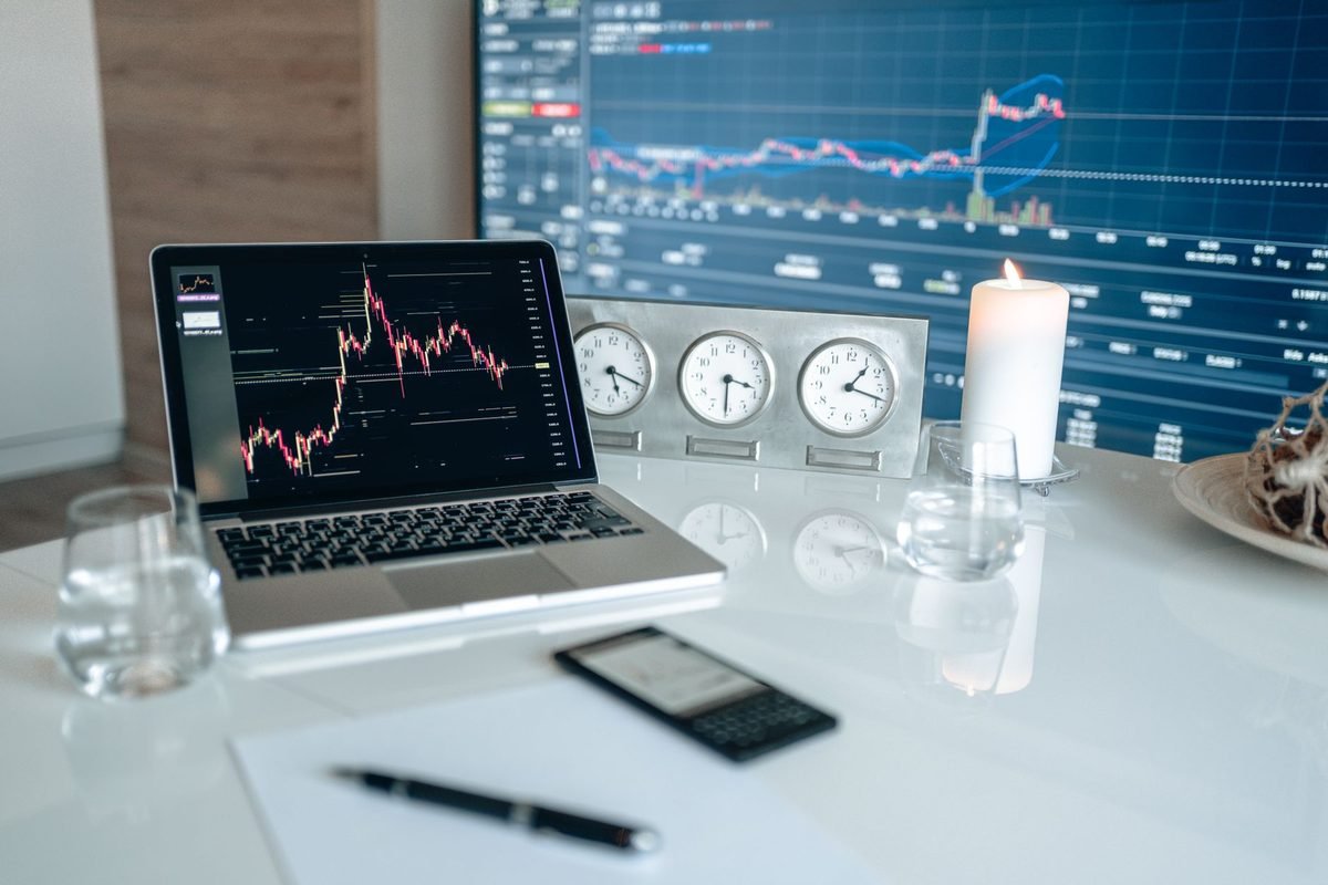 Portátil abierto con la pantalla de una plataforma de trading y gráficos de cotización